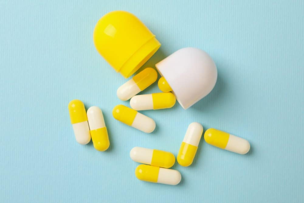 White yellow pills on blue background, close up